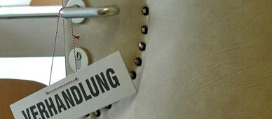 Blick auf ein Sitzungszimmer durch eine halbgeöffnete Tür. An der Türklinke hängt ein Schild 'Verhandlung'. (Foto: UVS)